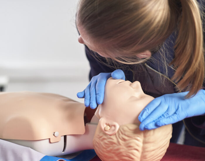 Eine Person übt die Atmungsüberprüfung an einer Puppe.