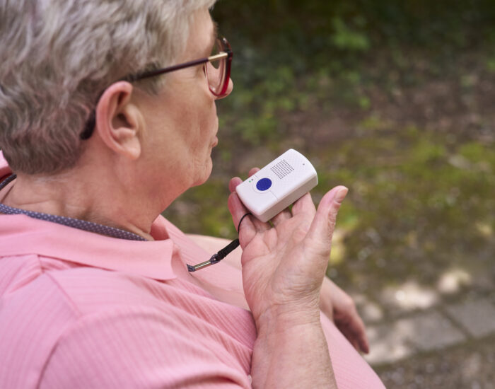 Eine Dame benutzt das mobile Hausnotrufgerät